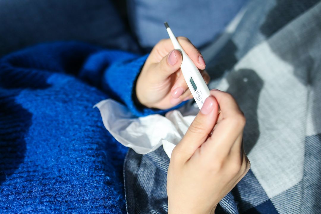 A person holding a thermometer - learn how IV hydration therapy can help you prevent common illnesses like the cold or flu.