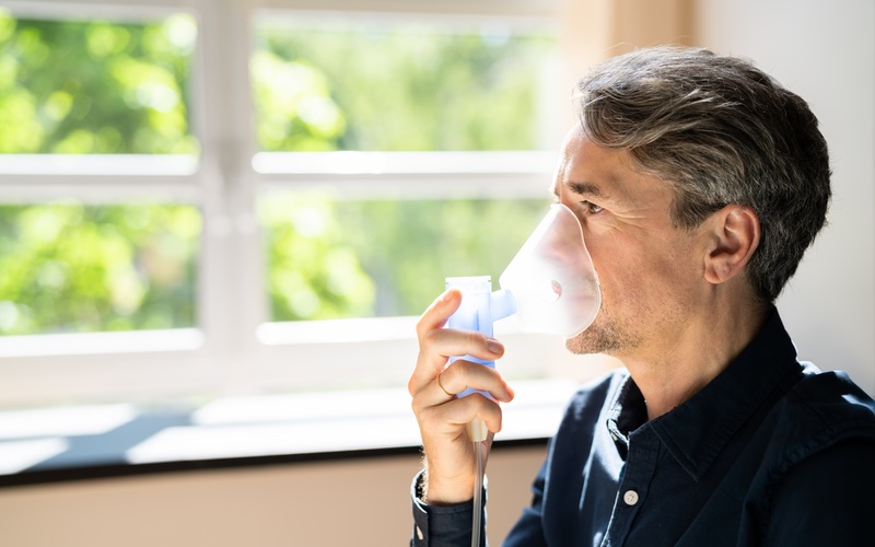 A man using a device to help clear his airways - discover CF symptom relief with Vida-Flo Buckhead.
